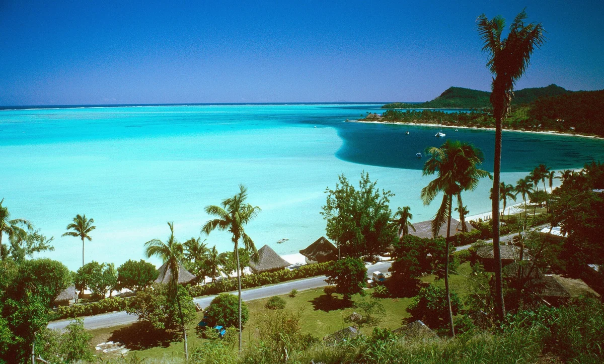 Matira beach with white sand and palm trees on the Bora Bora shore, French Polynesia